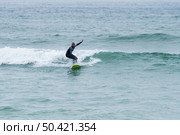 Surfer riding waves with a soft board in Furadouro beach, Portugal. Men catching waves in ocean. Surfing action water board sport. Стоковое фото, агентство Ingram Publishing / Фотобанк Лори