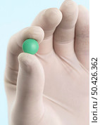 hand with latex glove holding pill. Стоковое фото, агентство Ingram Publishing / Фотобанк Лори