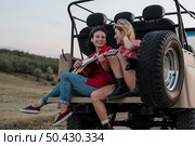 female friends playing guitar while traveling by car. Стоковое фото, агентство Ingram Publishing / Фотобанк Лори
