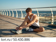 man tying his shoelaces beach before working out. Стоковое фото, агентство Ingram Publishing / Фотобанк Лори