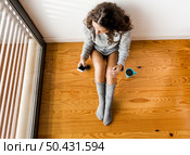 Woman sitting on the floor drinking a coffee and texting. Стоковое фото, агентство Ingram Publishing / Фотобанк Лори