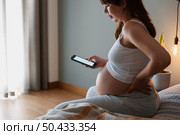 Painful pregnant young woman at home calling medical assistance on phone . Стоковое фото, агентство Ingram Publishing / Фотобанк Лори