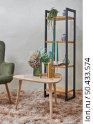 Idea of modern home interior decoration with arm chair, coffee table, fluffy rug or carpet and lots decorative elements such as, candles, vase with flowers, candle snuffer and house plant shelving.. Creative idea of home interior decorations. Стоковое фото, агентство Ingram Publishing / Фотобанк Лори