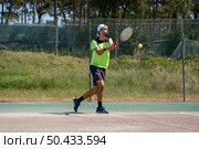 Tennis player hitting backhand at ball with racket on court. Стоковое фото, агентство Ingram Publishing / Фотобанк Лори