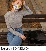 blond woman with medical mask sitting bench. Стоковое фото, агентство Ingram Publishing / Фотобанк Лори
