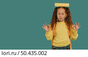 school girl with yellow shirt holding book head copy space. Стоковое фото, агентство Ingram Publishing / Фотобанк Лори