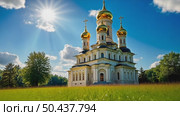 A majestic white Orthodox church with golden domes stands in a park with colorful autumn trees under a blue sky with clouds. Стоковое AI-видео, аниматор Sergey Grishin / Фотобанк Лори