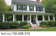 Front side of typical american porch colonial house with white traditional columns and pillars, beautiful garden in the back and forest behind backyard on background. Стоковое AI-видео, аниматор Sergey Grishin / Фотобанк Лори
