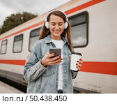 front view woman listening music railway station. Редакционное фото, агентство Ingram Publishing / Фотобанк Лори