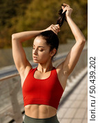 pretty young woman tying her hair up. Стоковое фото, агентство Ingram Publishing / Фотобанк Лори