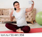 pregnant woman lotus position taking selfie. Стоковое фото, агентство Ingram Publishing / Фотобанк Лори