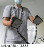 doctor with medical mask stethoscope using defibrillator. Стоковое фото, агентство Ingram Publishing / Фотобанк Лори