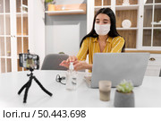 female vlogger home with laptop hand sanitizer. Стоковое фото, агентство Ingram Publishing / Фотобанк Лори