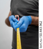 front view man with gloves holding tape measurer social distancing. Стоковое фото, агентство Ingram Publishing / Фотобанк Лори