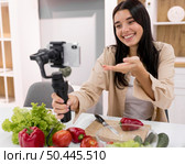 woman vlogging home with smartphone vegetables. Стоковое фото, агентство Ingram Publishing / Фотобанк Лори