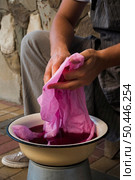 side view man squeezing cloth from natural pigment. Стоковое фото, агентство Ingram Publishing / Фотобанк Лори
