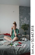 Teenage girl in casual clothes planning tasks with notebooks, pens, and markers on bed, drinking coffe, demonstrating comfort and focus while studying in cozy personal space. Стоковое видео, видеограф Енваев Андрей / Фотобанк Лори