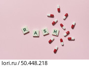 Rash word formed of scrabble blocks and pharmaceutical pills scattered over pink background. Skin disease and medical treatment concept.. Rash formed of scrabble blocks and pharmaceutical pills. Стоковое фото, агентство Ingram Publishing / Фотобанк Лори