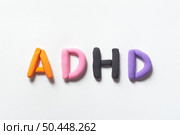 ADHD abbreviation formed of colorful plasticine on white background. Attention deficit hyperactivity disorder and mental health awareness.. ADHD formed of scrabble blocks. Стоковое фото, агентство Ingram Publishing / Фотобанк Лори