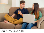 Young couple sitting on the sofa and watching something on a laptop. Стоковое фото, агентство Ingram Publishing / Фотобанк Лори