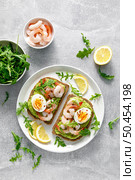 Toast with shrimps, avocado guacomole, arugula and boiled egg, top view. Стоковое фото, агентство Ingram Publishing / Фотобанк Лори