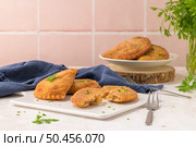 Meat patties and parsley leaves on white ceramic dishes in a kitchen counter top. Стоковое фото, агентство Ingram Publishing / Фотобанк Лори