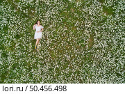 Beautiful girl lies in camomile daisy flower. View from above. Aerial photography. Стоковое фото, агентство Ingram Publishing / Фотобанк Лори