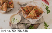Indian samosas  - fried or baked pastry with savoury filling, popular Indian snacks, served in areca leaf dishes with spices on kitchen countertop. Стоковое фото, агентство Ingram Publishing / Фотобанк Лори
