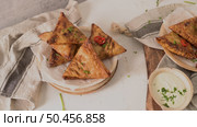 Indian samosas  - fried or baked pastry with savoury filling, popular Indian snacks, served in areca leaf dishes with spices on kitchen countertop. Стоковое фото, агентство Ingram Publishing / Фотобанк Лори