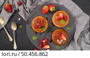 Caramel custard puddings on round slate on and dark kitchen countertop. Стоковое фото, агентство Ingram Publishing / Фотобанк Лори