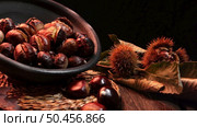Roasted chestnuts on a rustic wooden table with autumn leaves in the background. Стоковое фото, агентство Ingram Publishing / Фотобанк Лори