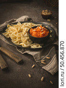 Farfalle pasta in a ceramic plate with pumpkin puree and pine nuts in a small ceramic bowl on a dark stone kitchen counter top. Стоковое фото, агентство Ingram Publishing / Фотобанк Лори