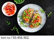 Toasts with salted salmon, arugula, green olives and cucumber, top down view. Стоковое фото, агентство Ingram Publishing / Фотобанк Лори