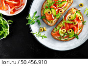 Toasts with salted salmon, arugula, green olives and cucumber, copy space, top down view. Стоковое фото, агентство Ingram Publishing / Фотобанк Лори