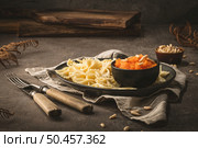 Farfalle pasta in a ceramic plate with pumpkin puree and pine nuts in a small ceramic bowl on a dark stone kitchen counter top. Стоковое фото, агентство Ingram Publishing / Фотобанк Лори