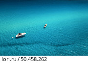 Aerial view of beautiful luxury yacht and boat in blue sea at sunset in summer. Sardinia island, Italy. Top view of speed boat, sea coast, azure clear water. Travel. Tropical landscape. Yachting . Стоковое фото, агентство Ingram Publishing / Фотобанк Лори