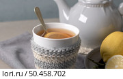 Cup of hot tea with lemon dressed in knitted warm winter scarf on wooden tabletop. Стоковое фото, агентство Ingram Publishing / Фотобанк Лори