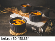 Creme brulee. Bowls with French vanilla cream dessert with caramelised sugar on top, spoons, dark rustic table. Стоковое фото, агентство Ingram Publishing / Фотобанк Лори