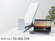 KYIV, UKRAINE - JANUARY 24, 2023: Starlink antenna, wi-fi router and laptop with Starlink software on display on white desk, houseplant in background. Necessities for remote work. Редакционное фото, агентство Ingram Publishing / Фотобанк Лори