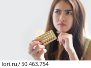 Young woman holding condom and contraceptive pills prevent pregnancy. Стоковое фото, агентство Ingram Publishing / Фотобанк Лори