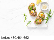 Tuna toast. Open sandwiches with whole grain bread, canned tuna, boiled egg, avocado and arugula. Top view. Стоковое фото, агентство Ingram Publishing / Фотобанк Лори