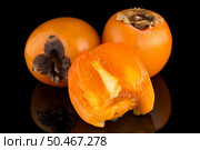 Persimmon fruits on black background. Стоковое фото, агентство Ingram Publishing / Фотобанк Лори