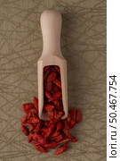 Top view of wooden scoop with dry red goji berries against green vinyl background. Стоковое фото, агентство Ingram Publishing / Фотобанк Лори