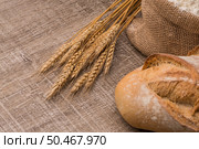Rustic bread and wheat on an old vintage planked wood table. Стоковое фото, агентство Ingram Publishing / Фотобанк Лори