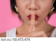 Beauty asian woman red lips and finger showing hush silence sign. Стоковое фото, агентство Ingram Publishing / Фотобанк Лори