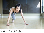 Young women warms up before exercising by pushing the floor and bending his knees in Gym. Стоковое фото, агентство Ingram Publishing / Фотобанк Лори