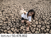The girl sat elsewhere, hand to the sky to ask for rain on the dry ground,global warming. Стоковое фото, агентство Ingram Publishing / Фотобанк Лори