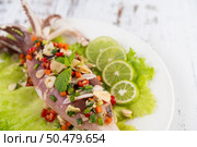 Spicy lemon squid with galangal, chilies, carrots, peppermint, spring onions and garlic on a plate on a white wooden floor. Стоковое фото, агентство Ingram Publishing / Фотобанк Лори