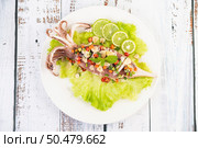 Spicy lemon squid with galangal, chilies, carrots, peppermint, spring onions and garlic on a plate on a white wooden floor. Стоковое фото, агентство Ingram Publishing / Фотобанк Лори