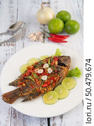 Fried tilapia with chili sauce, lemon salad and garlic on a plate on a white wooden table. Стоковое фото, агентство Ingram Publishing / Фотобанк Лори